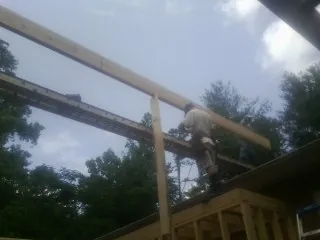 Carpenter setting a ridge beam over a new addition frame — Ice Dam Removal by Roofing Brothers in Claremore