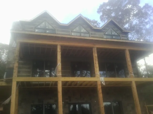 Dormers and porch framing on a large log home under construction — Roof Coating work by our crew in Claremore