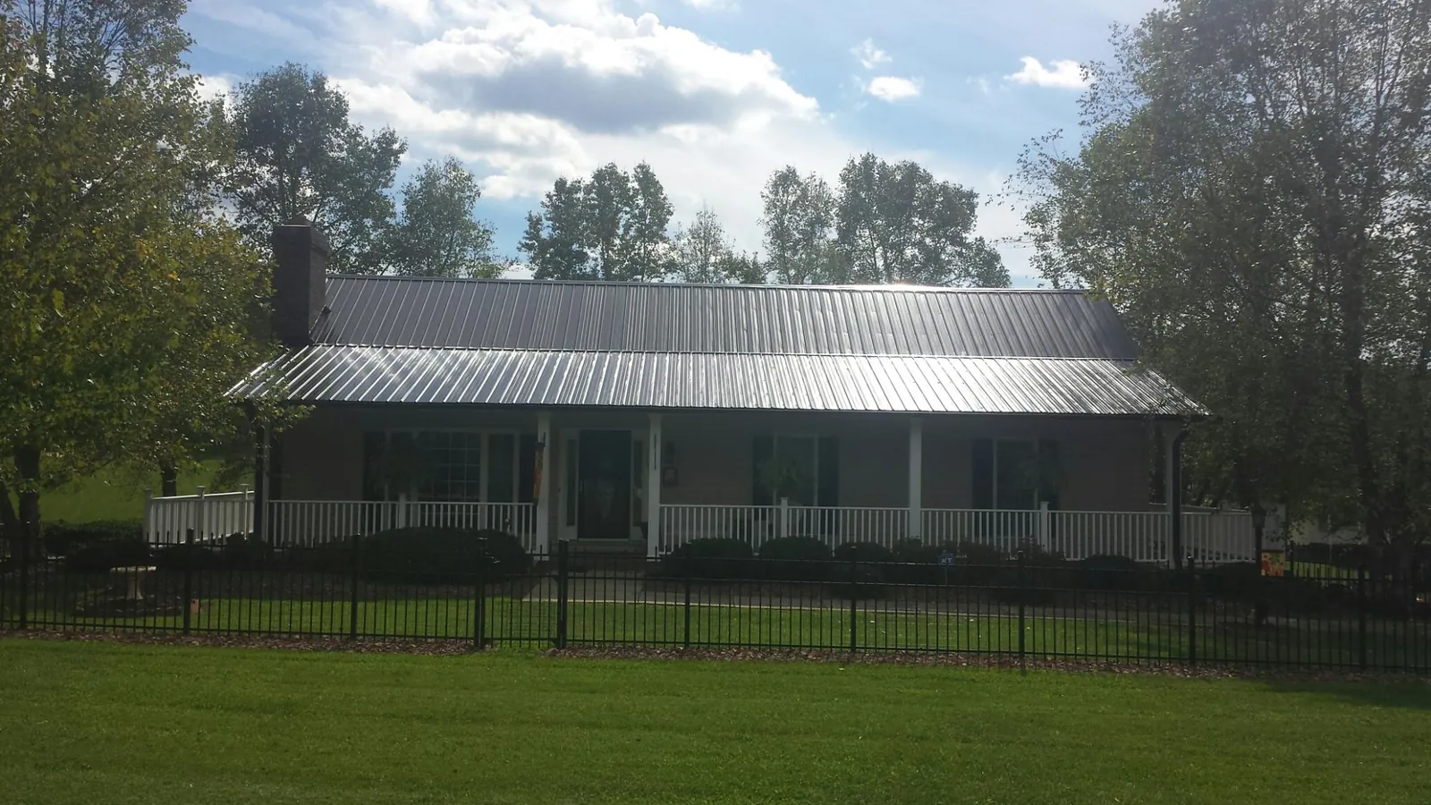 Gray metal roof on a brick ranch with a full width front porch — Gutter Guard Installation work by our crew in Claremore