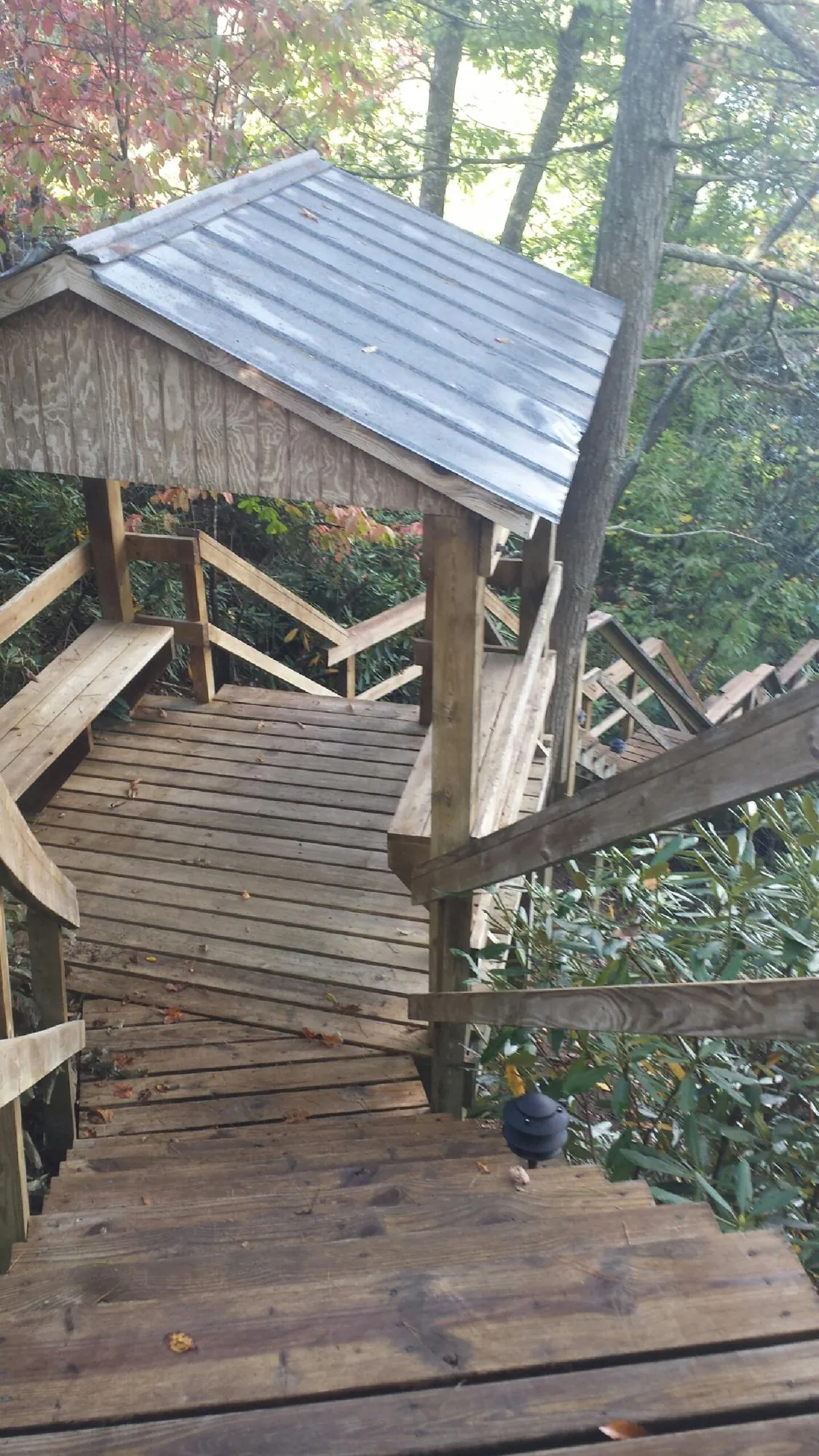 Metal roofed shelter over wooden steps on a wooded walkway — Skylight Repair & Installation work by our crew in Claremore